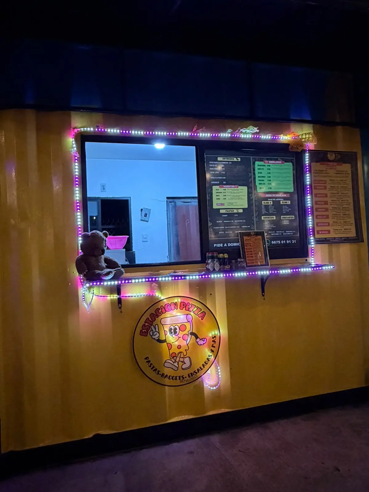 Contenedor amarillo de Estación Pizza con luces de colores en la ventanilla
