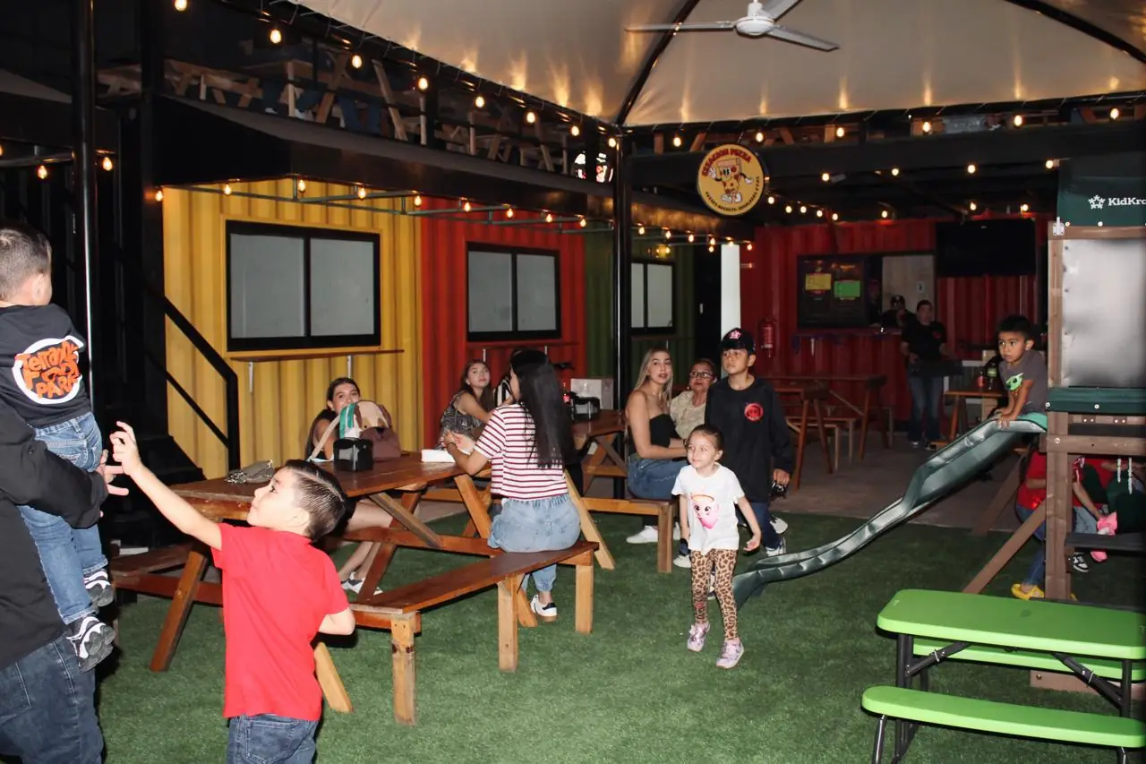 Familias en las mesas del food park mientras los niños juegan