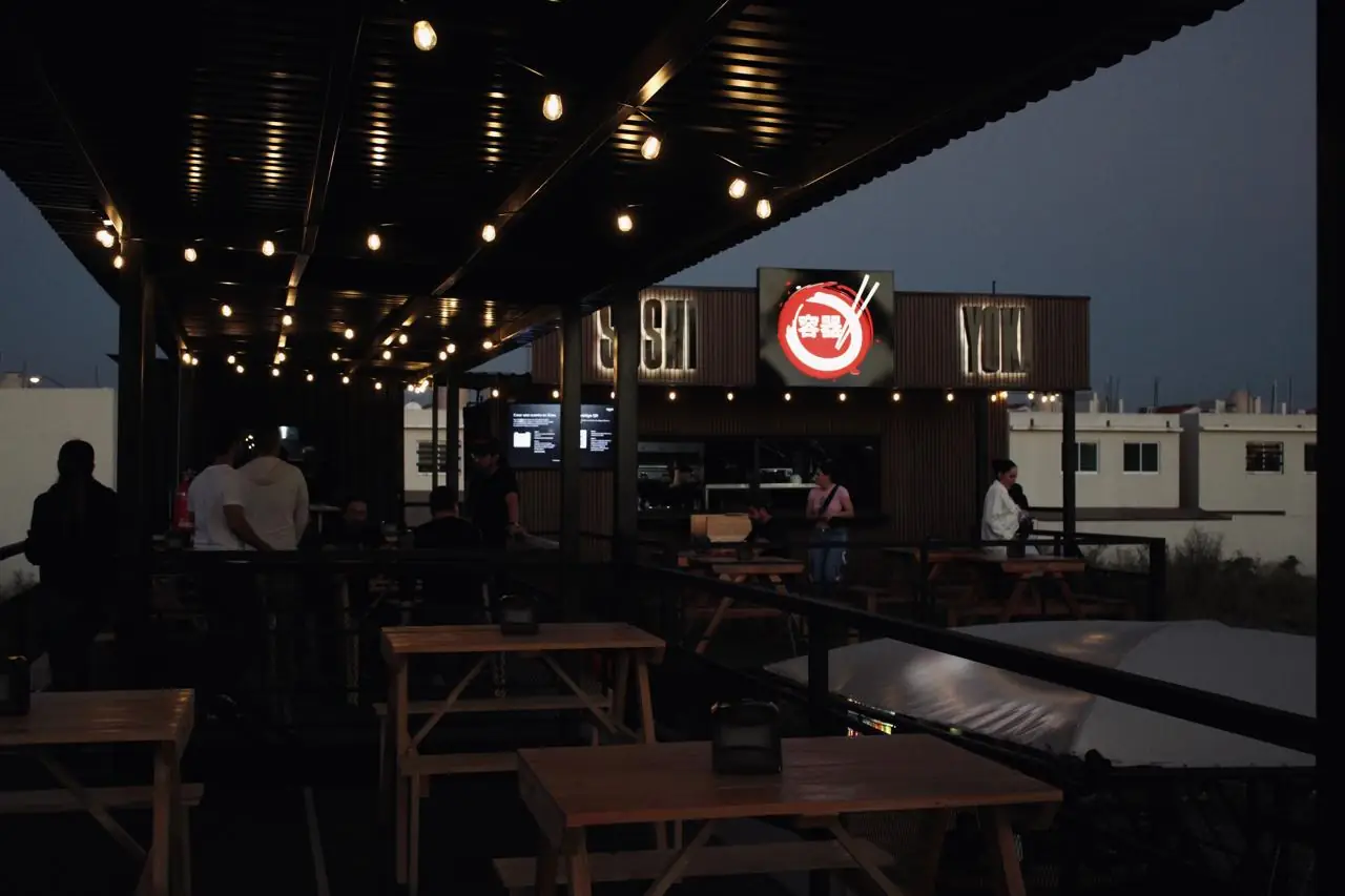 Terraza de Terranova Food Park al anochecer con foquitos colgando sobre las mesas